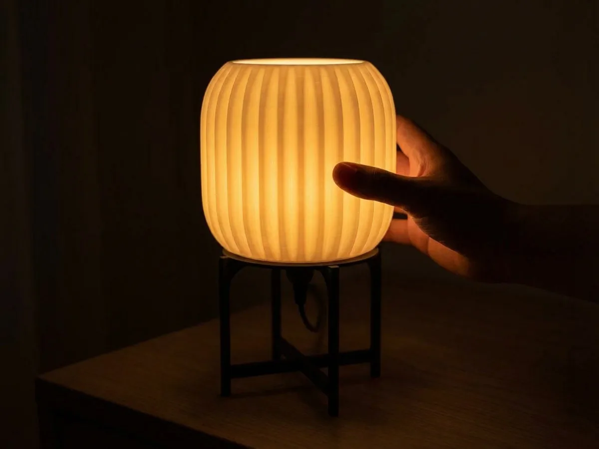 Hand holding LampuKita lamp to show scale — approximately 20cm tall